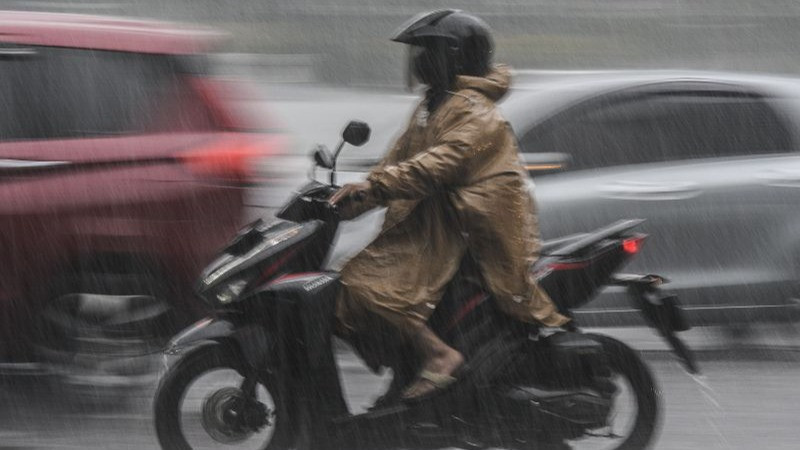 Pengendara motor melintas saat hujan