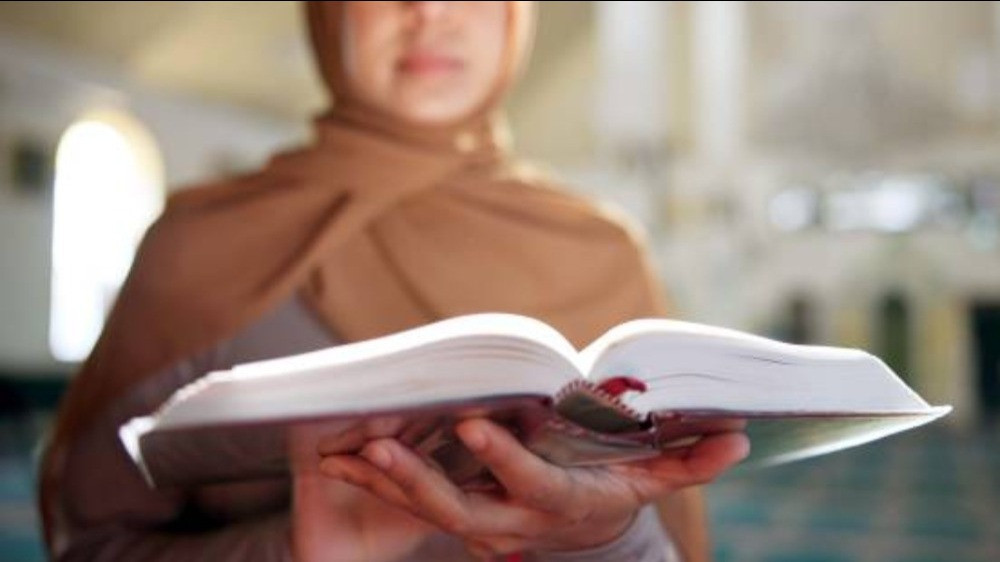 Ilustrasi wanita memakai jilbab membaca Al Quran