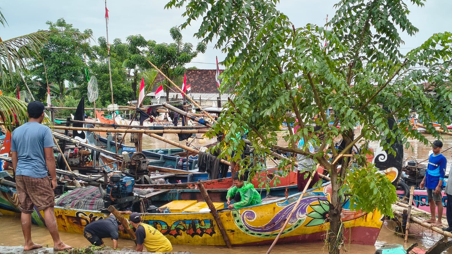 Para nelayan Desa Sambiroto, Tayu, Pati sedang gotong royong menurunkan perahu-perahu yang kandas sampai ke atas tanggul akibat banjir bandang, Sabtu (10/1/2026).