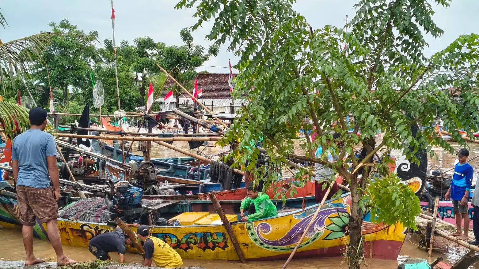 Para nelayan Desa Sambiroto, Tayu, Pati sedang gotong royong menurunkan perahu-perahu yang kandas sampai ke atas tanggul akibat banjir bandang, Sabtu (10/1/2026).