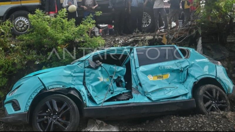 Warga mengamati taksi listrik Green SM yang rusak pascakecelakaan dengan KRL