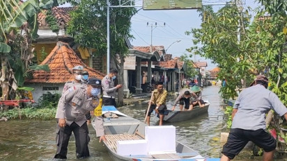 Hampir Satu Bulan Banjir Belum Surut, Polisi Bagikan Bantuan Gunakan Perahu