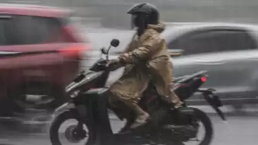Pengendara motor melintas saat hujan