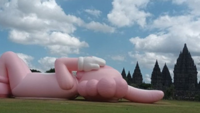Patung Ikonik KAWS 'Rebahan Santai' di Candi Prambanan