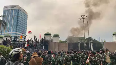 Situasi rusuh yang memperlihatkan massa yang berhasil menaiki pagar tinggi kompleks Gedung DPR RI, Jumat (29/8/2025) sore,