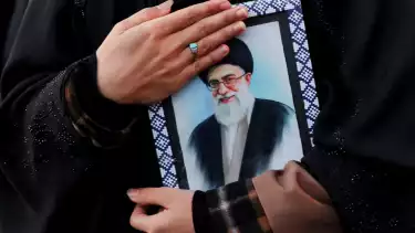 Seorang perempuan memegang foto Pemimpin Tertinggi Iran Ayatollah Ali Khamenei di Enghelab Square, Teheran, Iran, Minggu (1/3/2026), setelah ia dilaporkan tewas dalam serangan Israel dan Amerika Serikat.